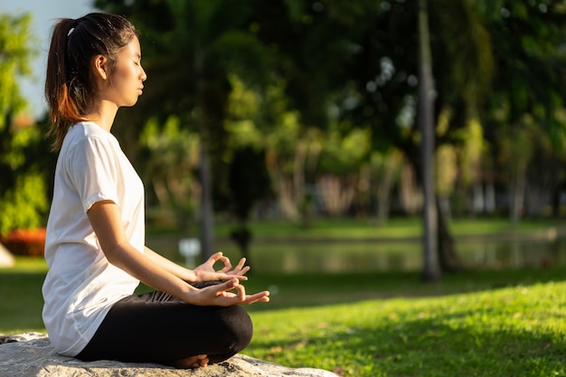 Mujer asiática haciendo ejercicios de yoga en el parque