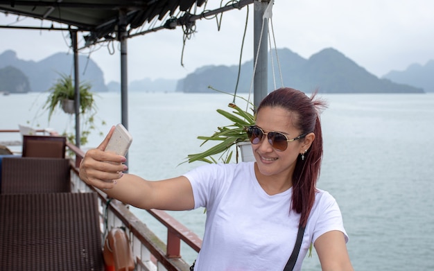 Foto mujer asiática haciendo tomar una foto usted mismo por la cámara del teléfono inteligente con hermoso paisaje