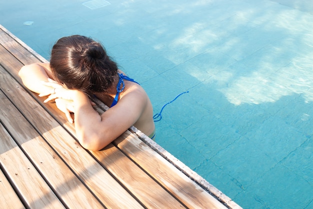 Mujer asiática hermosa que se relaja en piscina.