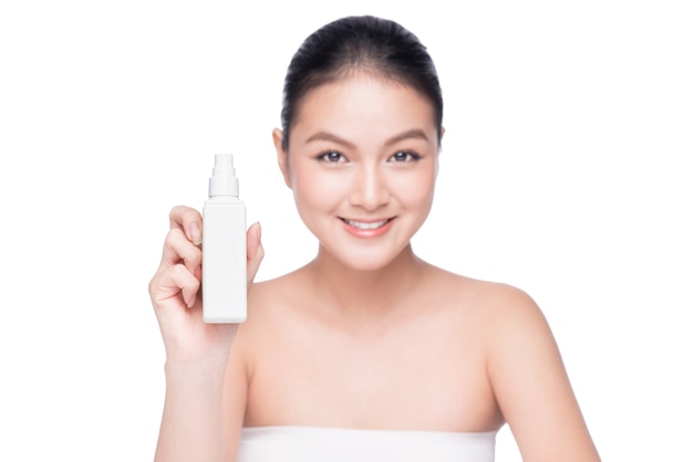 Mujer asiática hermosa que sostiene la botella de agua del aerosol aislado fondo blanco.