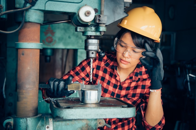 Mujer asiática hermosa que trabaja con la máquina en el ingeniero de fábrica y el concepto de mujer trabajadora o día de la mujer