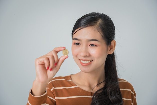 Mujer asiática hermosa sonriente que mira la moneda