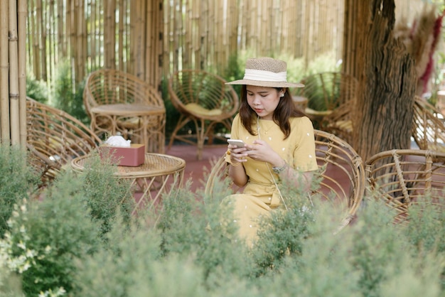 Mujer asiática con una hermosa sonrisa leyendo buenas noticias en el teléfono móvil durante el descanso en la cafetería mujer feliz viendo sus fotos en el teléfono celular mientras se relaja en la cafetería durante el tiempo libre