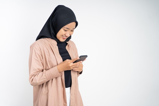 Mujer asiática en hiyab sonriendo mientras usa un teléfono celular