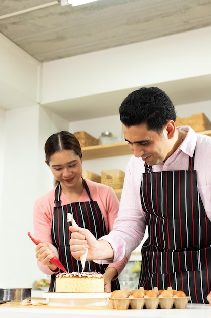 Una mujer asiática y un hombre árabe como pareja de adultos jóvenes aprenden a hacer panadería cocinando pasteles en línea curso de cocina Diverse Family video to cyberspace class on laptop as blogger social media together copy space