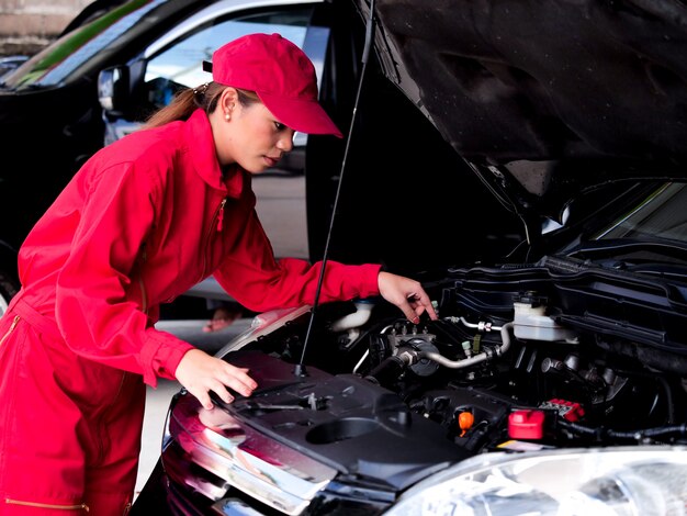 Mujer asiática de ingeniería que comprueba el coche.