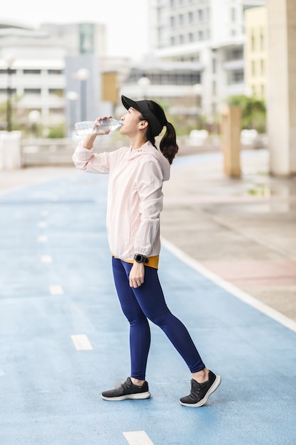 Foto una mujer asiática joven y activa que está bebiendo la botella de agua.