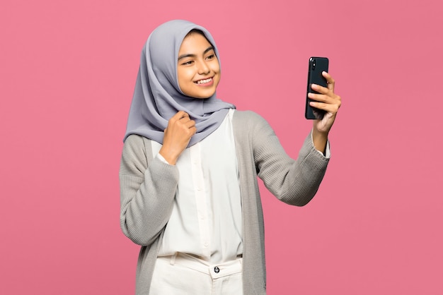 Mujer asiática joven alegre que parece feliz en la videollamada en el teléfono móvil