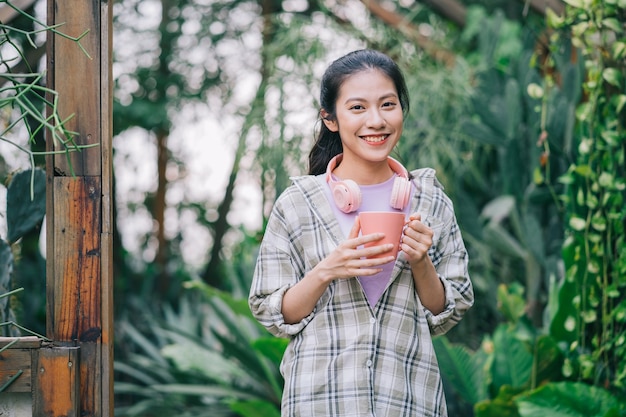 Mujer asiática joven bebiendo té en el jardín