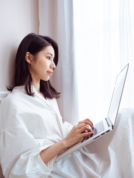 Mujer asiática joven con computadora en casa