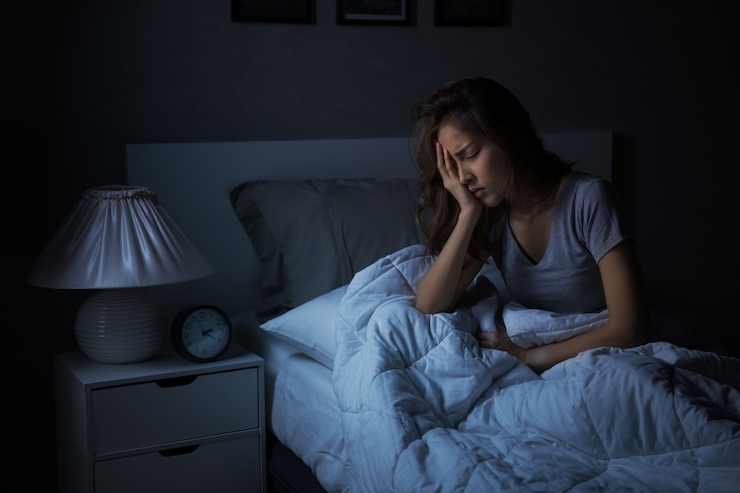 Foto mujer asiática joven deprimida sentada en la cama no puede dormir por insomnio