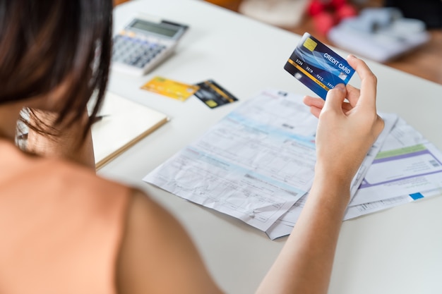 Mujer asiática joven estresada que sostiene la tarjeta de crédito y sin dinero para pagar la deuda de la tarjeta de crédito