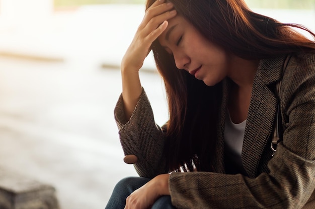 Una mujer asiática joven estresada sentada sola