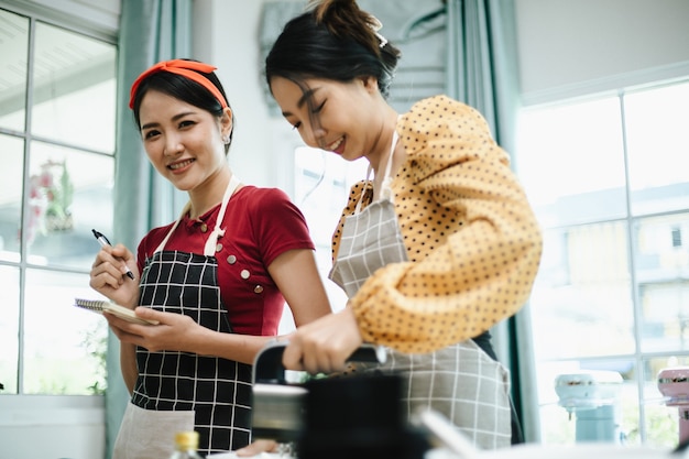 Una mujer asiática joven feliz en delantal, sonriendo y cocinando.