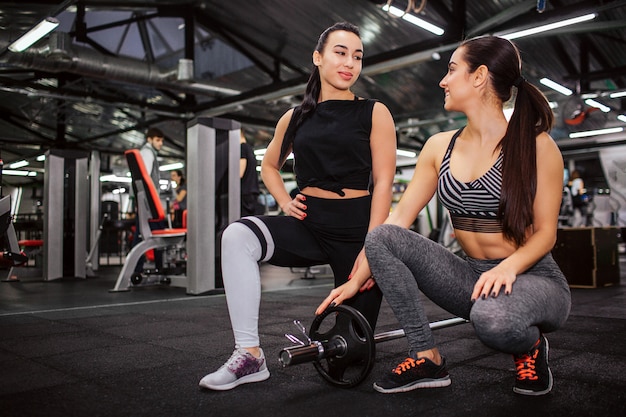 La mujer asiática joven hermosa se coloca en una rodilla y mira a su amiga.