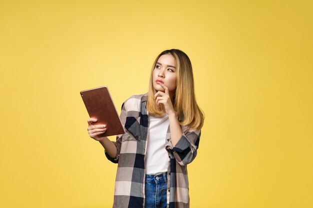 Mujer asiática joven hermosa que usa la tableta.