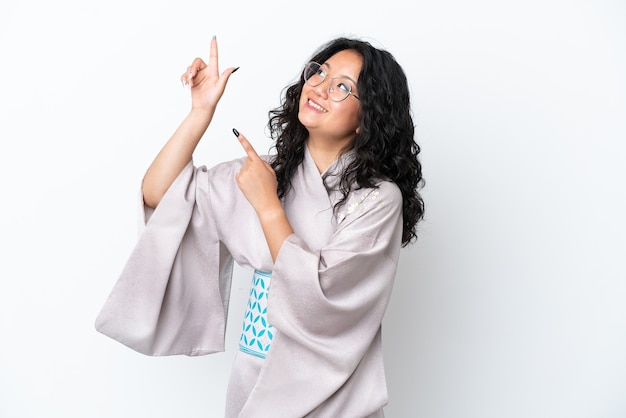 Mujer asiática joven con kimono aislado sobre fondo blanco apuntando con el dedo índice una gran idea