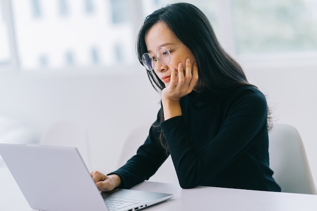 Mujer asiática joven con laptop en la oficina