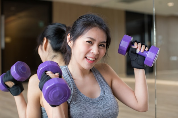 Mujer asiática joven mantenga entrenamiento de pesas en el gimnasio