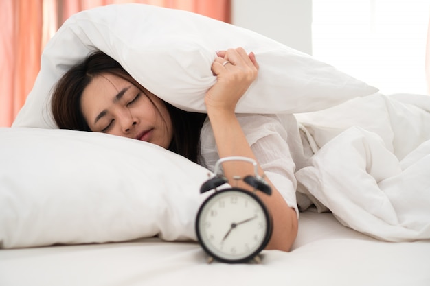 Foto mujer asiática joven perezosa que despierta en la madrugada para el trabajo diario rutinario.