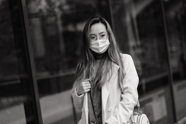 Mujer asiática joven con protección facial mascarilla quirúrgica. Ella viaja entre su casa y su lugar de trabajo en la ciudad.