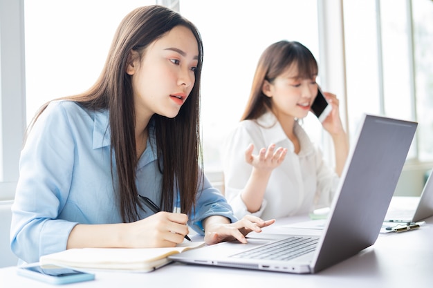 Mujer asiática joven que se centra en hacer el trabajo