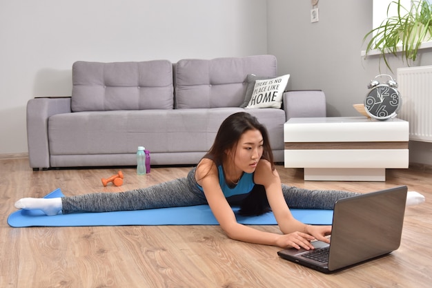 Mujer asiática joven que hace yoga en casa.