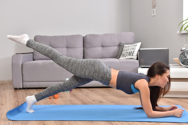 Mujer asiática joven que hace yoga en casa.