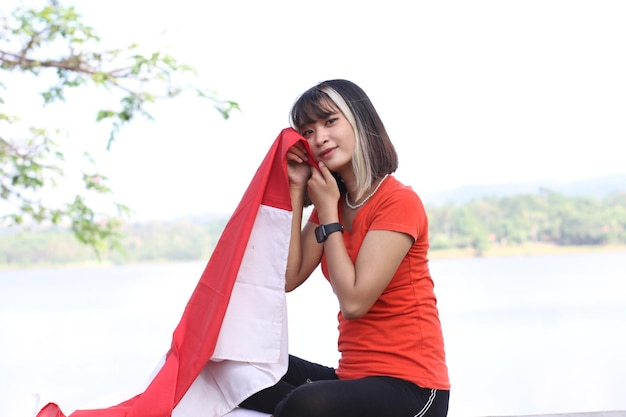 Foto mujer asiática joven que lleva la bandera indonesia