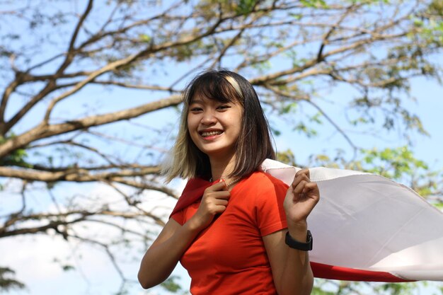 Foto mujer asiática joven que lleva la bandera indonesia