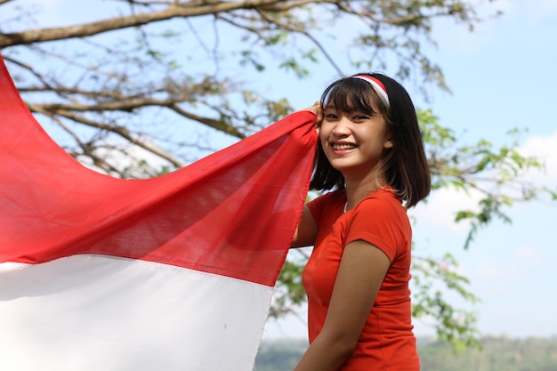 Foto mujer asiática joven que lleva la bandera indonesia