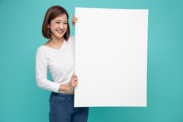 Mujer asiática joven que lleva a cabo el lado derecho el papel grande blanco.