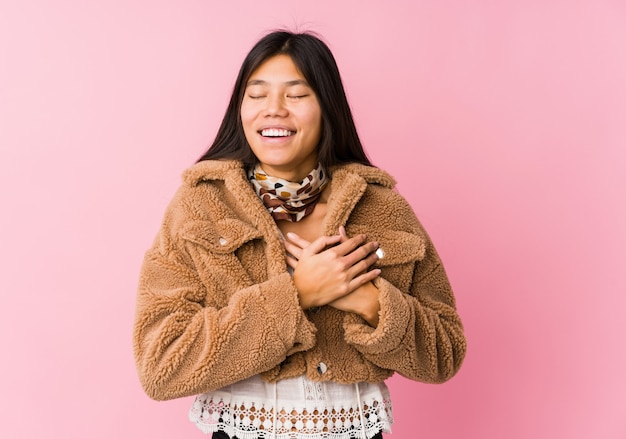 Mujer asiática joven que ríe manteniendo las manos en el corazón, concepto de felicidad.