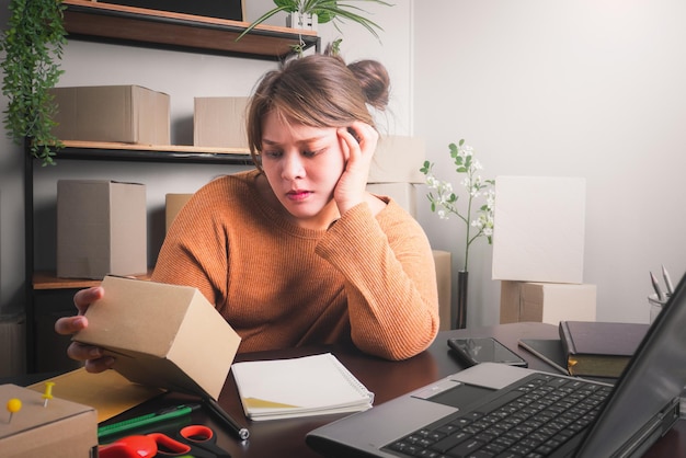 Mujer asiática joven que se siente estresada o deprimida frente al concepto de venta en línea de su computadora portátil