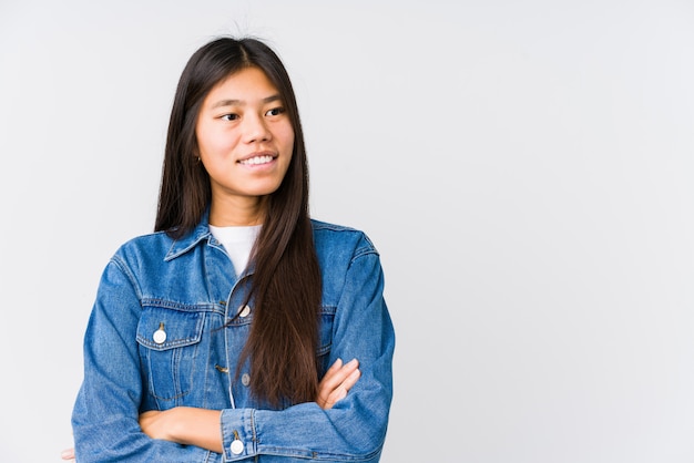 Mujer asiática joven que sonríe confiada con los brazos cruzados.