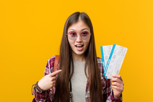 La mujer asiática joven que sostenía boletos aéreos sorprendió señalar a sí mismo, sonriendo ampliamente.