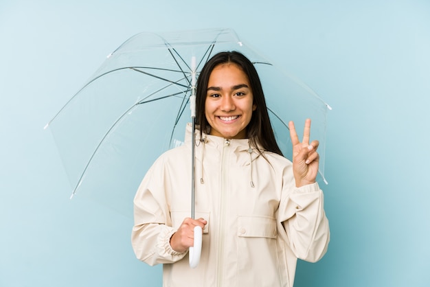 Mujer asiática joven que sostiene un paraguas que muestra el número dos con los dedos.