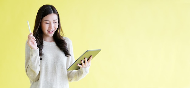 Mujer asiática joven que sostiene la tableta digital que sonríe