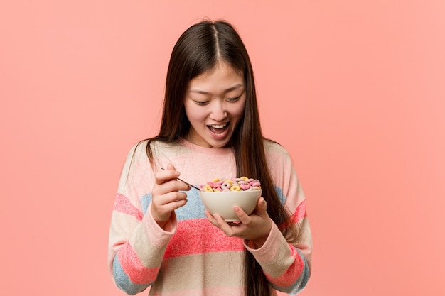 Mujer asiática joven que sostiene un tazón de cereal