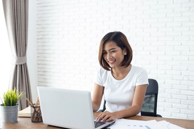 Mujer asiática joven que trabaja en la computadora portátil