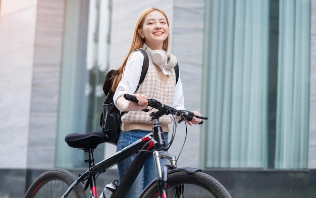 Mujer asiática joven que usa la bicicleta como medio de transporte