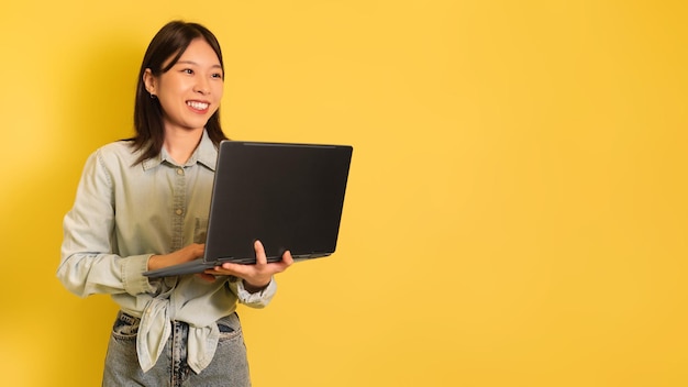 Mujer asiática joven que usa una computadora portátil que busca en Internet trabajando en línea revisando un nuevo sitio web mirando