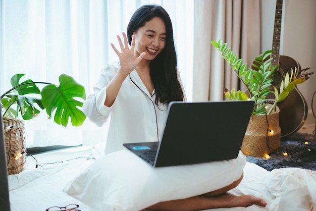 Mujer asiática joven que usa la computadora portátil para trabajar en línea de negocios, mujer independiente que trabaja desde casa utilizando la tecnología de comunicación del ciberespacio de Internet para el trabajo de empresaria