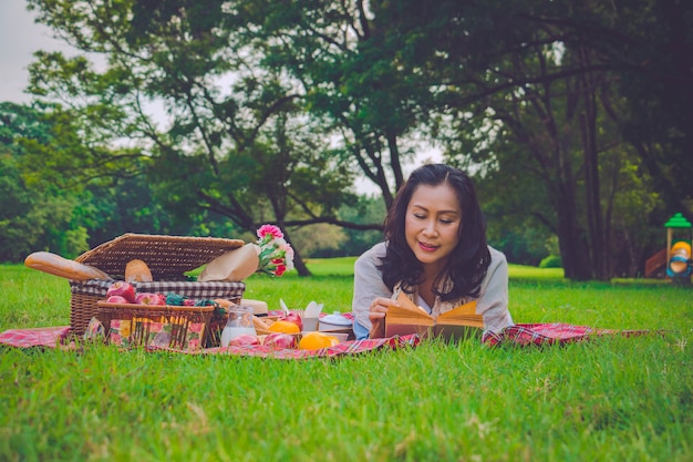 La mujer asiática joven relaja tiempo en parque