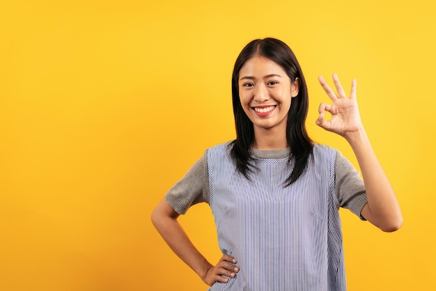 Foto mujer asiática joven en ropa casual poniendo las manos en la cintura con