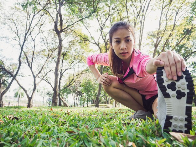 Mujer asiática joven sana que ejercita en el parque