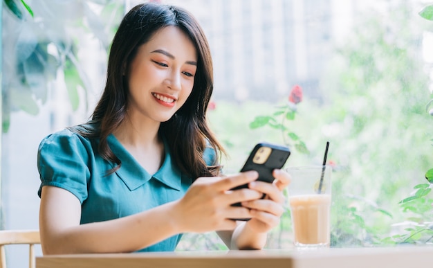 Mujer asiática joven con smartphone para trabajar en el café