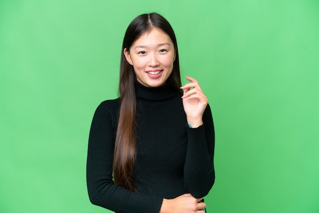 Mujer asiática joven sobre fondo clave de croma aislado riendo