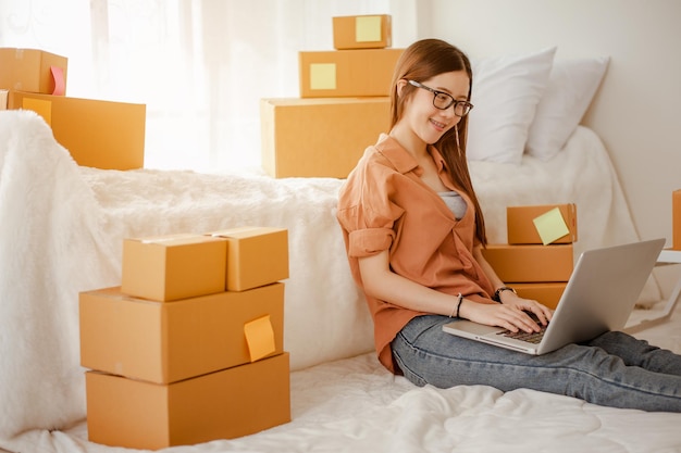 Mujer asiática joven trabaja desde casa hablando con clientes para vender productos en línea y entrega