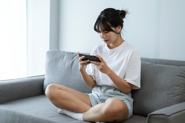 Mujer asiática jugando en el teléfono móvil chica jugadora jugando videojuegos sosteniendo Smartphone trabajando dispositivos móviles tecnología de telefonía celular concepto de comercio electrónico